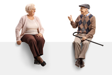 Wall Mural - Senior man talking to a senior woman while sitting on a blank panel