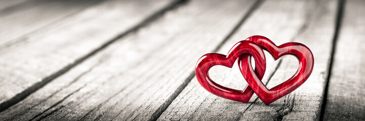 two red wooden interlocking hearts with high gloss finish on rustic wood table - valentine's day con
