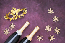 Two Champagne Bottles And Golden Carnival Mask On Purple Background. Flat Lay Of Christmas, New Year, Purim, Carnival Celebration Concept. Copy Space, Top View.