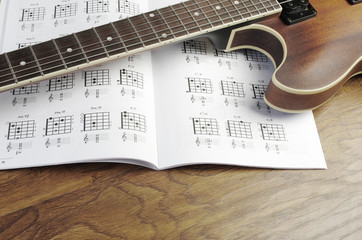 Electric guitar and chord book on a wooden texture