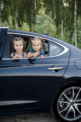 two little girls look through a car window