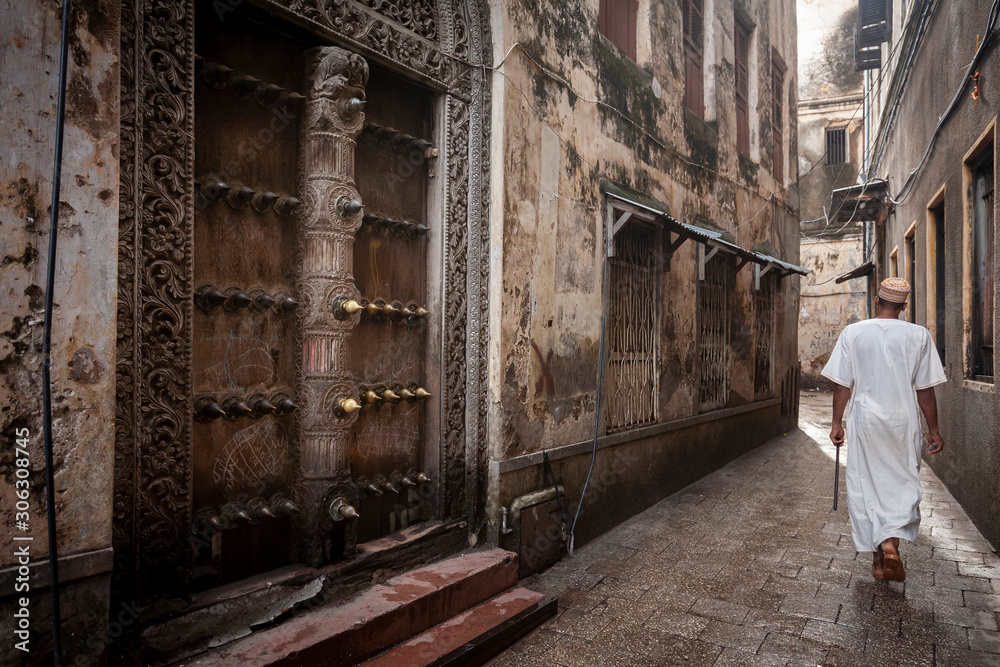 islamic man walking through narrow streets of Stonetown - obrazy, fototapety, plakaty 