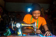 © Confidence - young african woman who is a tailor working on a dress smiling