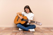 © luismolinero - Young woman with guitar sitting on the floor