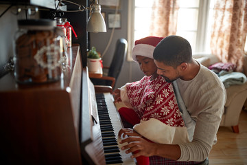 Wall Mural - Christmas, winter holidays, new year party and family concept. father with child  play music on piano.