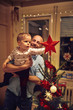 © luckybusiness - baby and father putting a star on the top of the Christmas tree