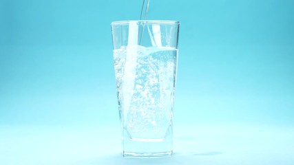 Sticker - water is poured into a glass on blue background