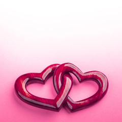 Wall Mural - two pink wooden interlocking hearts with high gloss finish on pink background - valentine's day / ma