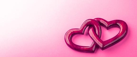 Wall Mural - two pink wooden interlocking hearts with high gloss finish on pink background - valentine's day / ma