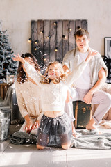 Christmas and new year theme. Parents and children at home playing with fake snow. Laughing joyful & emotions. Christmas 2020. The family catches snow.