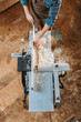 © LIGHTFIELD STUDIOS - top view of woodworker holding plank near circular saw in carpentry shop