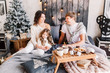 © Anastasia - Happy loving family mother, father and child on Christmas sit on the bed with a drink. New year 2020. Parents look at each other. A girl looks in frame and smiles. Parents play with their daughter.