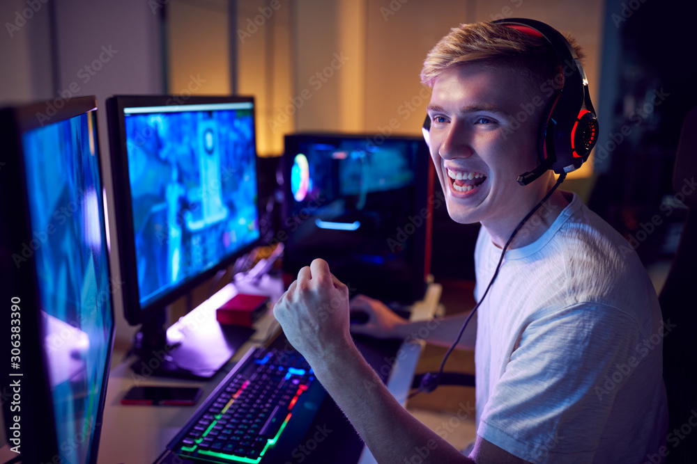 Teenage Boy Wearing Headset Gaming At Home Using Dual Computer Screens ...