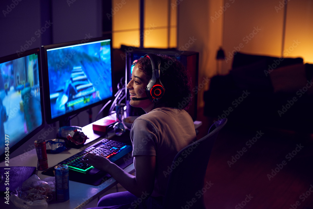 Teenage Girl Wearing Headset Gaming At Home Using Dual Computer Screens - obrazy, fototapety, plakaty 