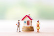 © pim pic - selective focus of miniature angry woman with miniature man and mini house on stack coins over blurred green garden background  for Asset management after divorce concept.