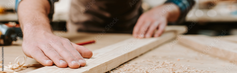 panoramic shot of carpenter touching wooden plank - obrazy, fototapety, plakaty 