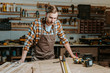 © LIGHTFIELD STUDIOS - handsome woodworker looking at table with wooden planks and measuring tape
