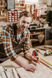 © LIGHTFIELD STUDIOS - cheerful woodworker holding pencil near wooden plank and measuring tape
