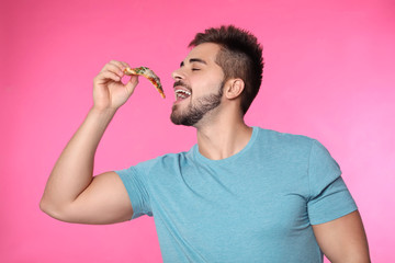 Wall Mural - Handsome man eating pizza on pink background