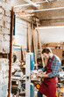© LIGHTFIELD STUDIOS - selective focus of bearded woodworker in goggles using cnc machine in workshop