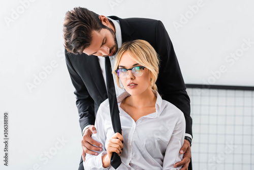 Fotografía Sexy businesswoman pulling tie of businessman in office