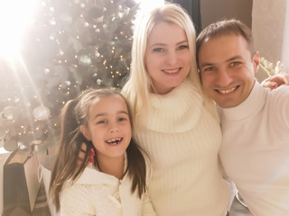 Wall Mural - Christmas. Family. Technology. View on the smartphone. Dad, mom and daughter looking at camera and smiling while doing selfie