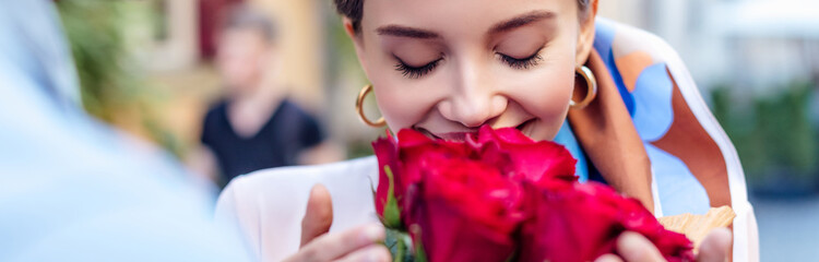 cropped view of man presenting bouquet of roses to happy girlfriend, panoramic shot