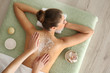 © New Africa - Young woman having body scrubbing procedure with sea salt in spa salon, top view