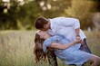 canvas print picture - Closeup shot of a romantic couple kissing each other in a grassy field with a blurred background