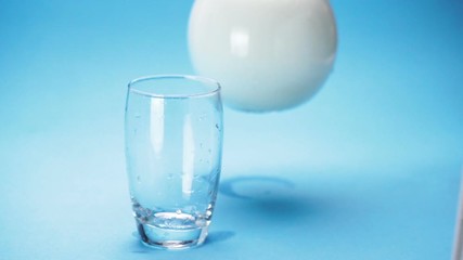 Wall Mural - milk is poured into a glass on blue background