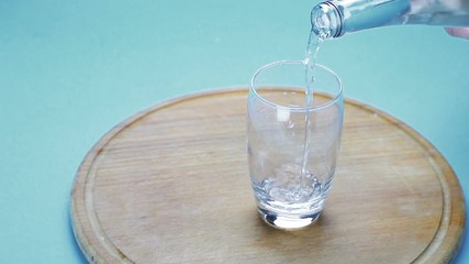 Sticker - water is poured into a glass on blue background