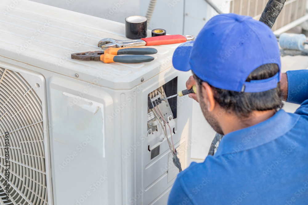 a professional electrician man is fixing a heavy duty unit of central ...