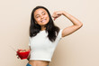 © Asier - Young asian woman holding a cereals bowl raising fist after a victory, winner concept.