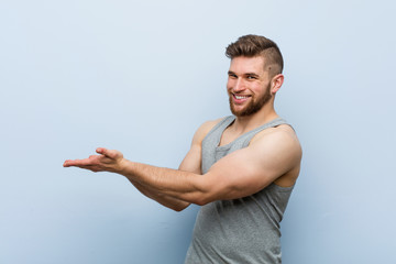 Wall Mural - Young handsome fitness man holding a copy space on a palm.
