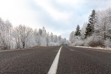 Winter Road At Frosty Day With Blue Sky, Landscape With Snow Covered Trees, Pattern Of White Highway Dividing Strip And Ice On Asphalt