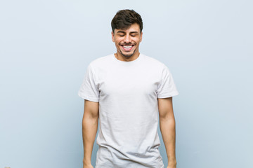 Wall Mural - Young caucasian man wearing a white tshirt laughs and closes eyes, feels relaxed and happy.