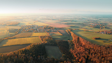 Wall Mural - Aerial countryside view from above with a small village and fields and autumn forest with colorful sunset tones. Germany