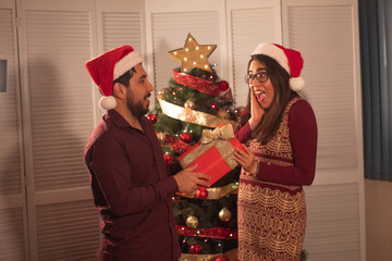 Joven pareja con árbol de navidad en fiestas estilo mexicano