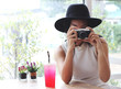© Phuttharak - Beautiful Asian tourist woman wearing black hat sitting in coffee shop by the window with red drink on table