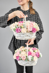 Wall Mural - Two Flowers arrangements in Wicker basket. Modern floral shop. Finished work of the florist. Cute bouquet of mixed flowers in womans hands. Delivery fresh cut flower from online store