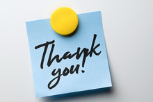 Close-up Note With Words Of Thanks Written In Handwritten Font Attached With A Magnet To A Metallic White Surface