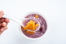 Hand Holding A Spoonful Of Nutritious And Delicious Sweet Potato Porridge On White Background