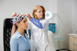 © DC Studio - Doctor adjusting neurology helmet during a brain scan procedure