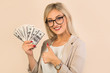 © Alexandr - beautiful young woman in a suit on a beige background with dollars in hand