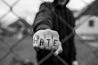 © Alpar - Aggressive teenage boy showing hes fist behind wired fence at the correctional institute, the word hate is written on hes hand, focus on the boys hand , conceptual image of juvenile delinquency .