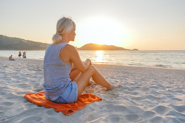 Wall Mural - Woman relaxing on a tropical beach at sunrise.