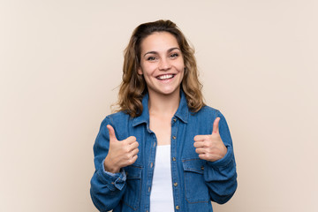 Wall Mural - Young blonde woman over isolated background giving a thumbs up gesture