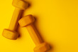 © Богдан Маліцький - yellow dumbbells lie on a yellow background, the concept of summer, training, sports