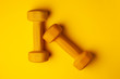 © Богдан Маліцький - yellow dumbbells lie on a yellow background, the concept of summer, training, sports