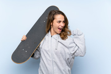 Wall Mural - Young blonde woman with skate and making victory gesture